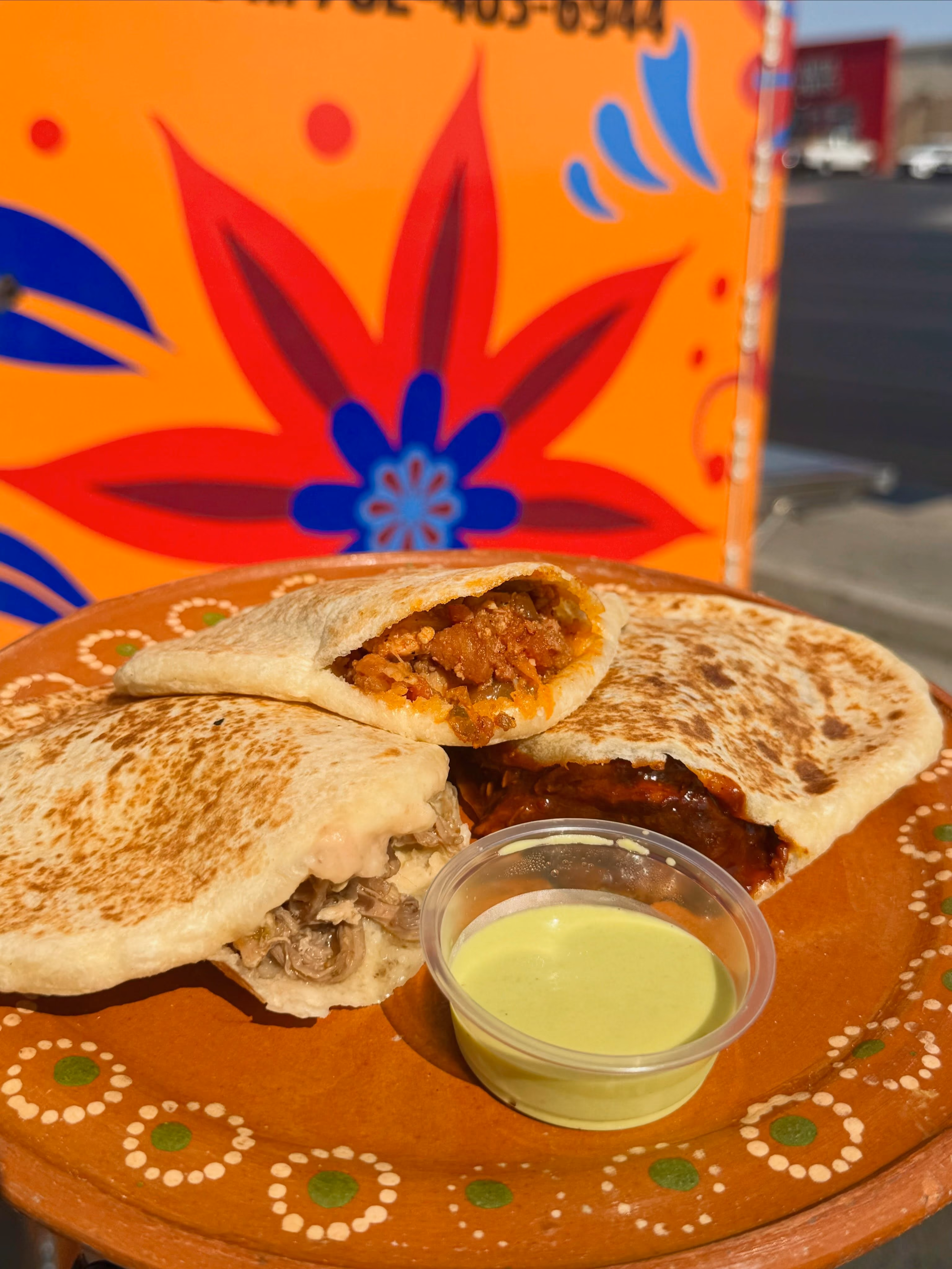 Three grilled quesadillas with different fillings served on a decorative plate with green sauce.