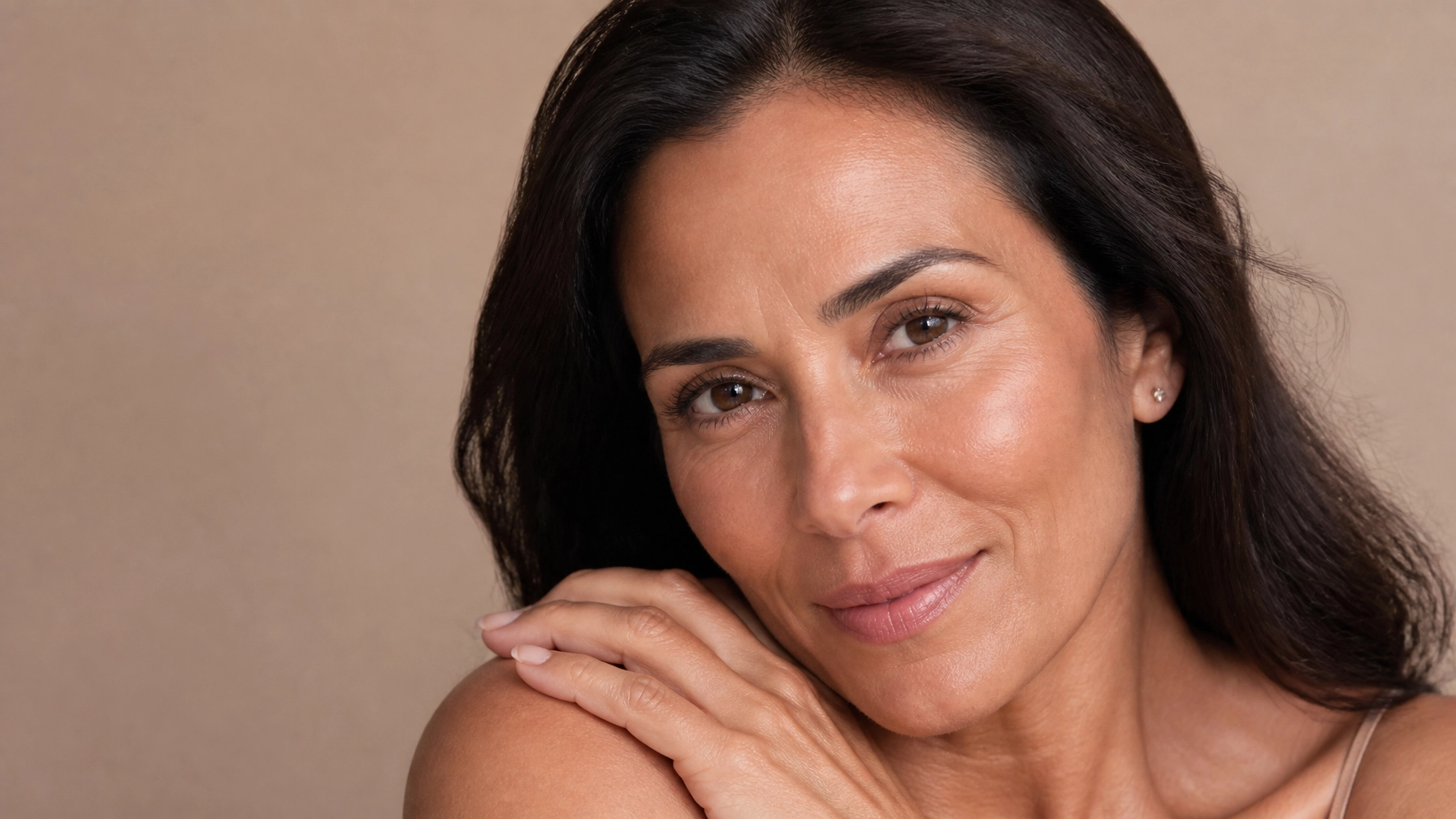 Realistic Hispanic woman in her 40s or 50s with healthy-looking skin in soft flattering light
