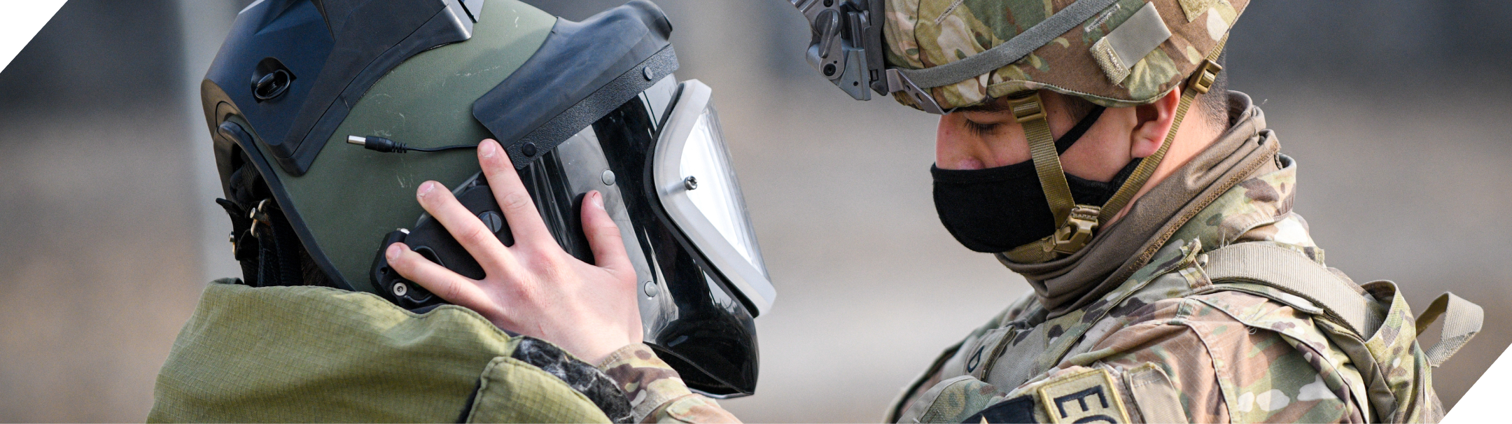 A U.S. soldier helps another adjust a protective helmet.