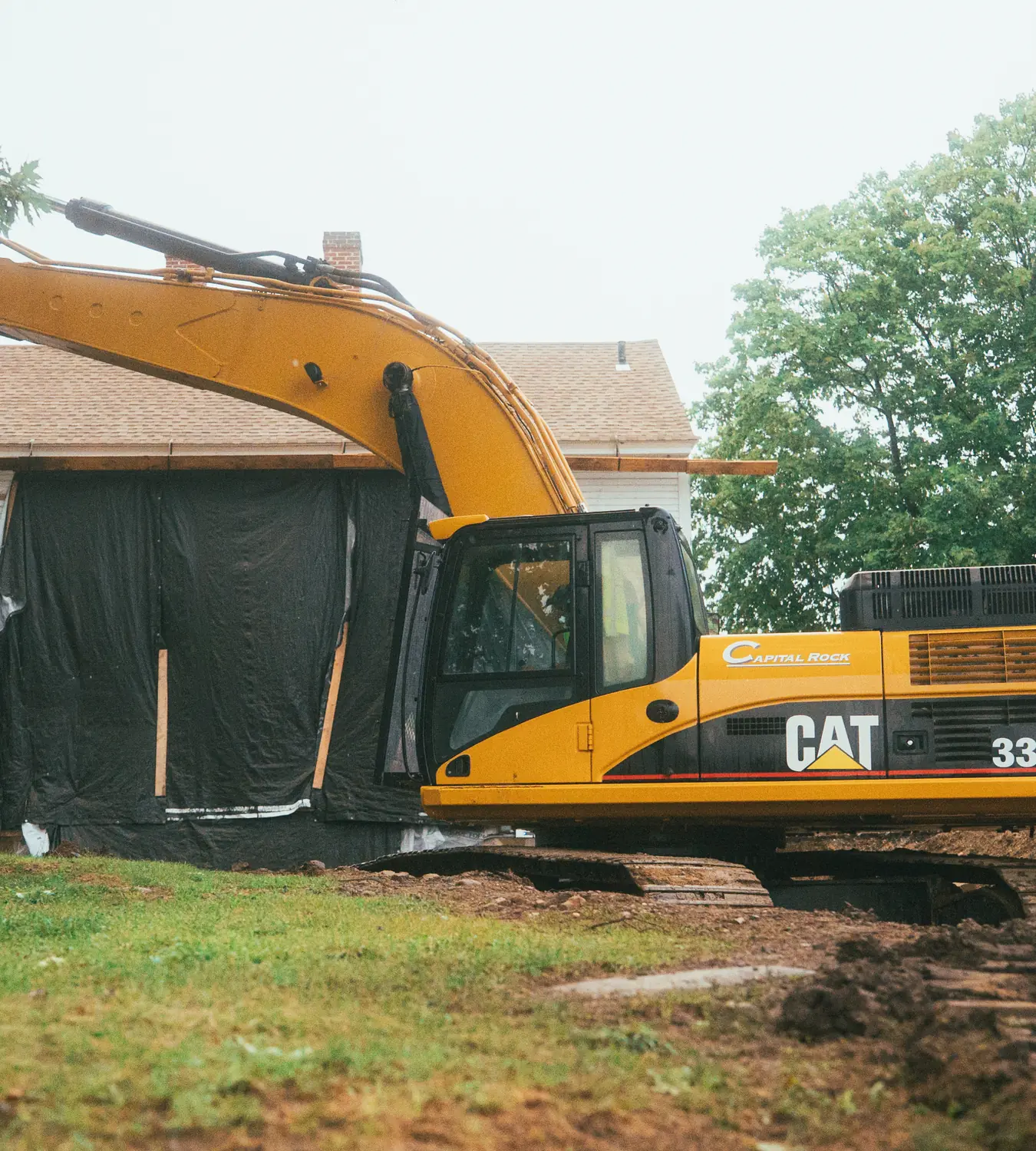 Excavator beside a house during residential sitework.