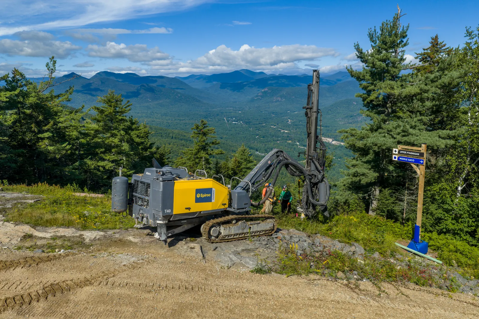 Drill rig and worker on a cleared mountain ridge