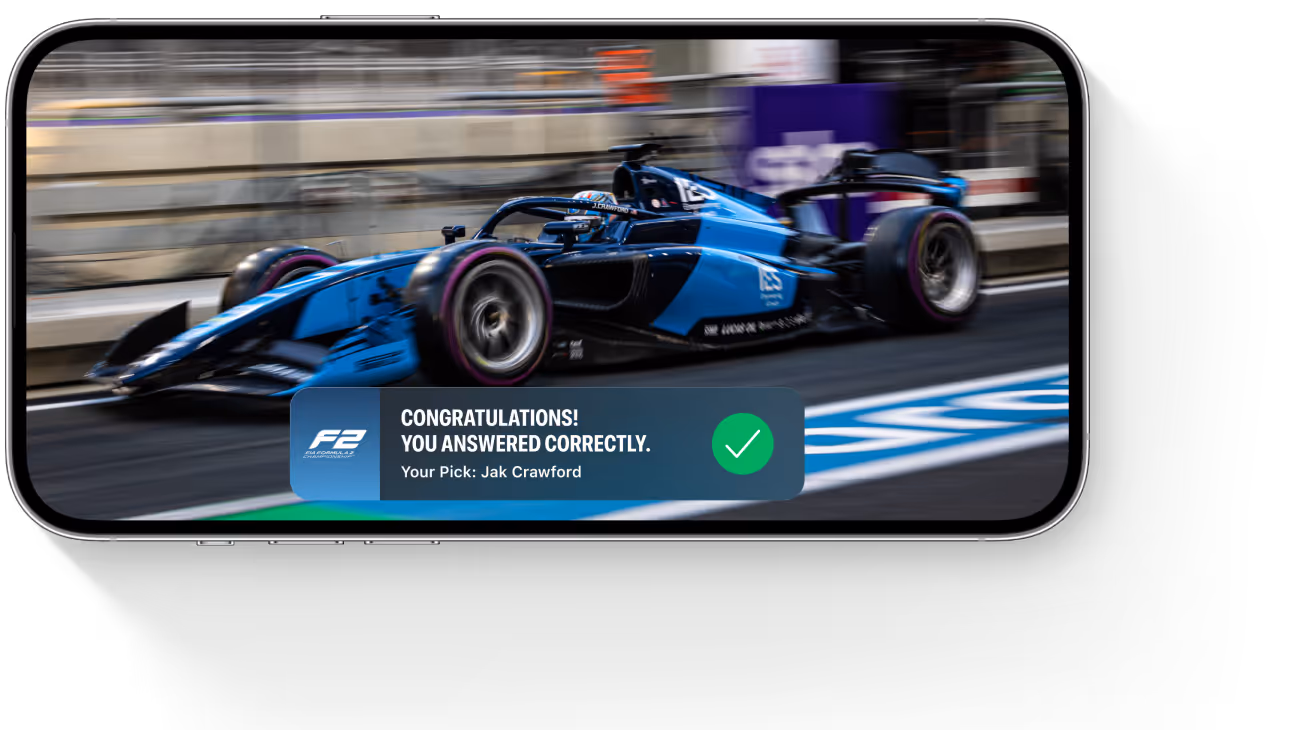 Smartphone screen displaying a blue Formula 2 car racing on a track with a congratulatory message for answering correctly.