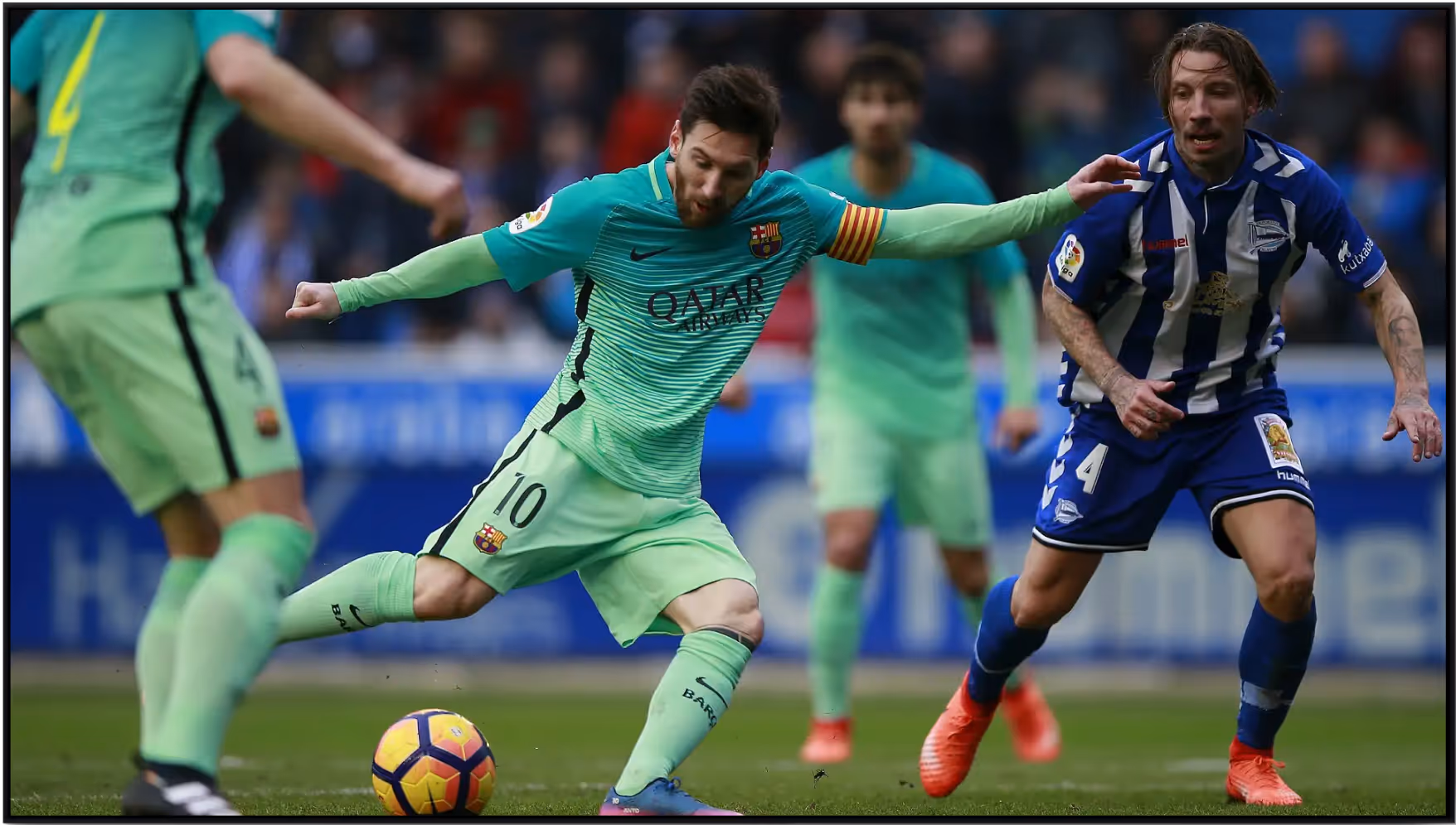 Soccer player Lionel Messi wearing a green Barcelona uniform with number 10, dribbling a yellow and purple ball while being defended by a player in a blue and white striped uniform.