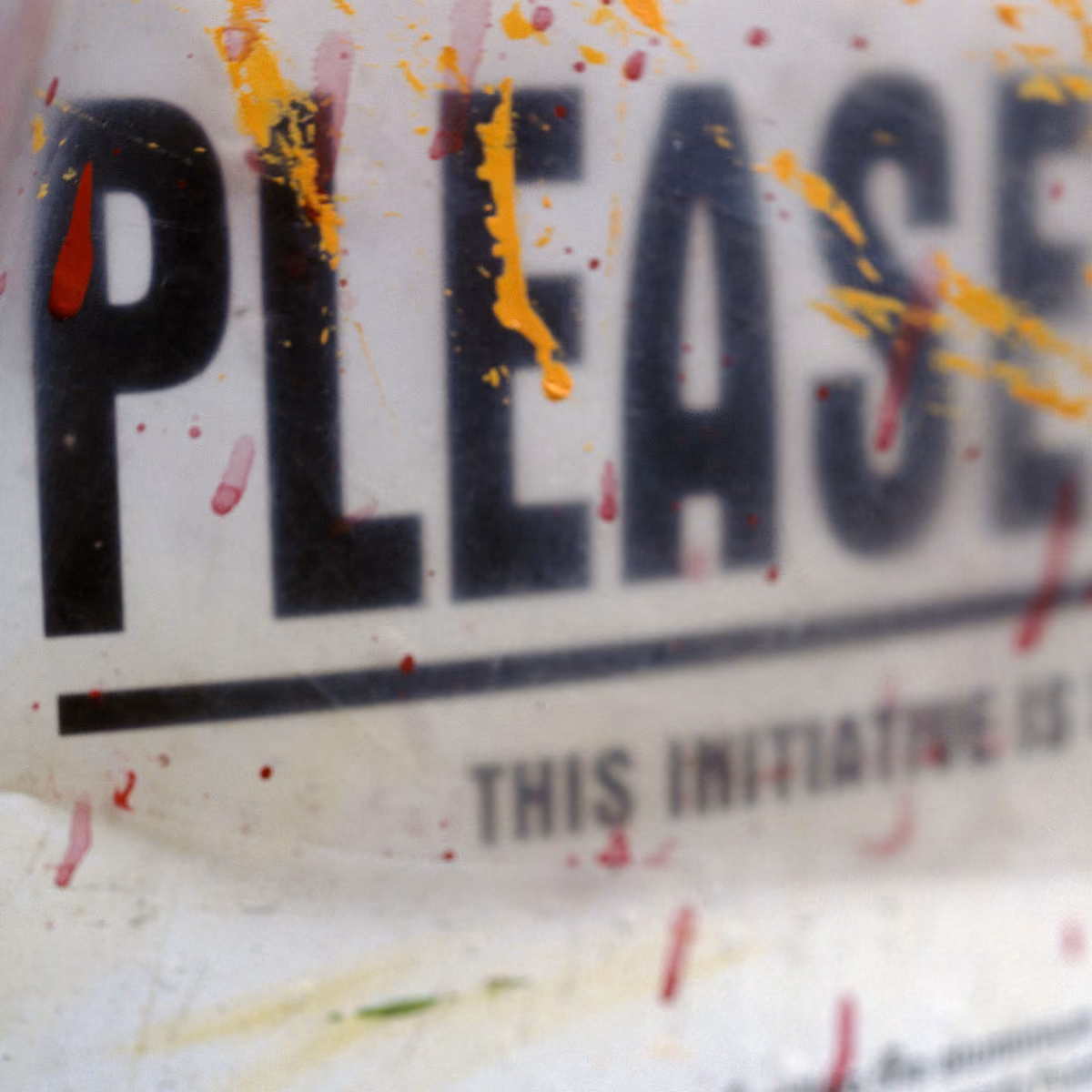 Close-up of splattered paint on a surface with the word 'PLEASE' in bold black letters.