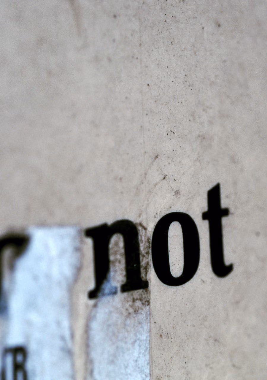 Close-up of the word 'not' in black type on a worn, textured white-gray surface.