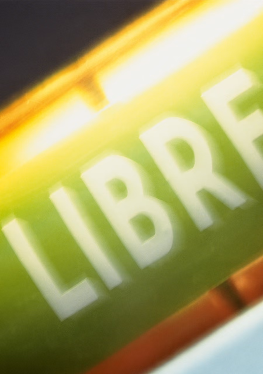 Close-up of glowing tube with the word LIBRE partially visible in white on green background.