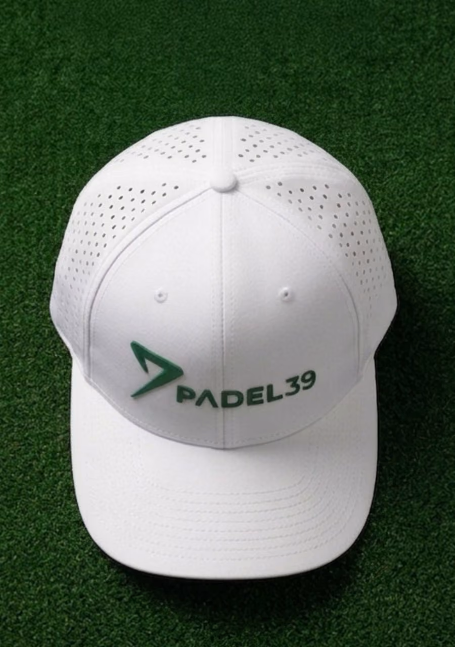 White cap with ventilation holes and green Padel39 logo placed on green turf.