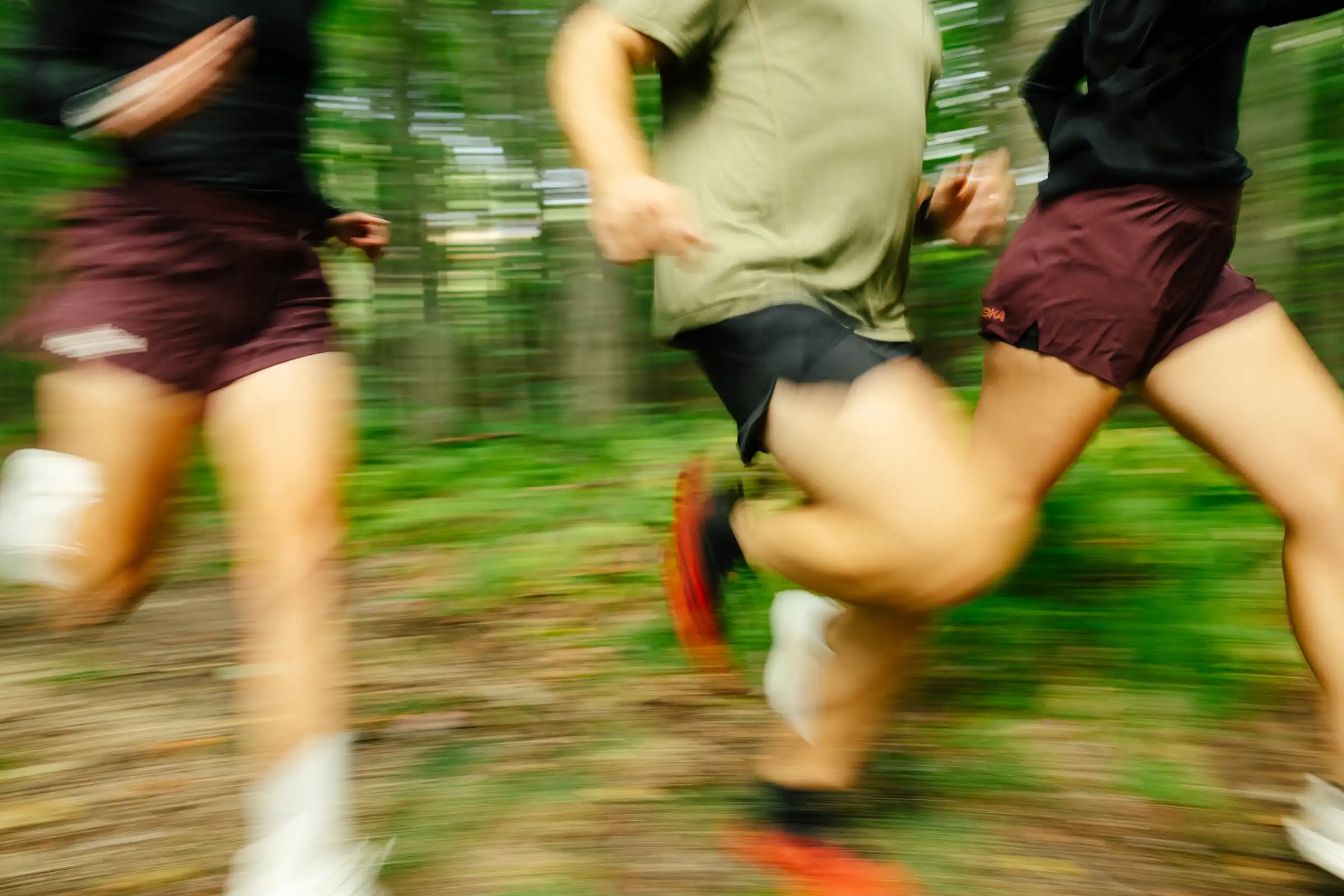 Jambes de coureurs en plein effort sur un sentier forestier, saisies en filé