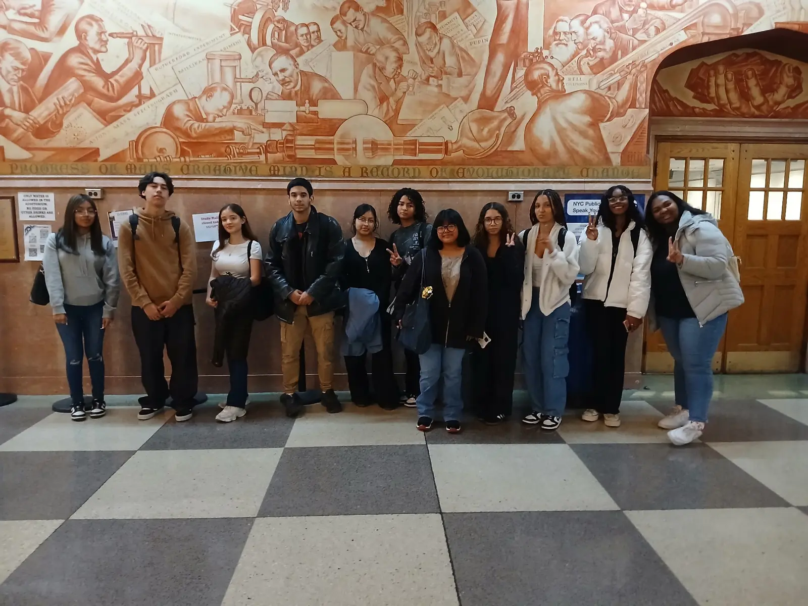 Students posing in front of a historic mural during field trip