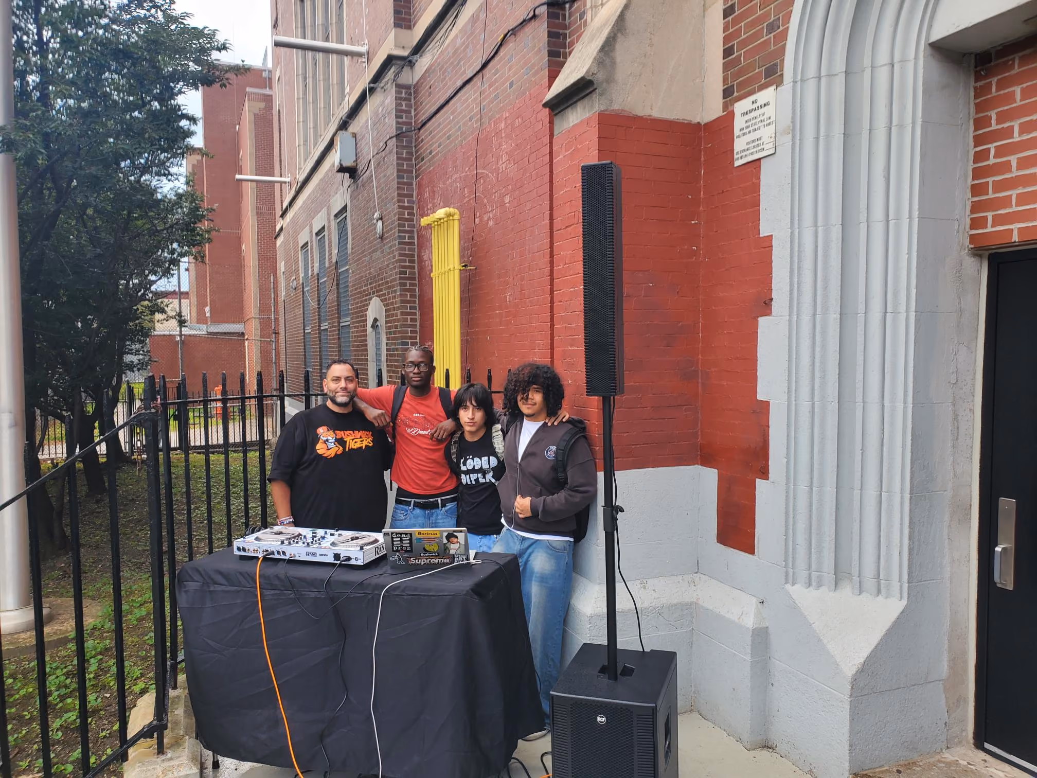 Students and staff posing beside DJ equipment outside school building