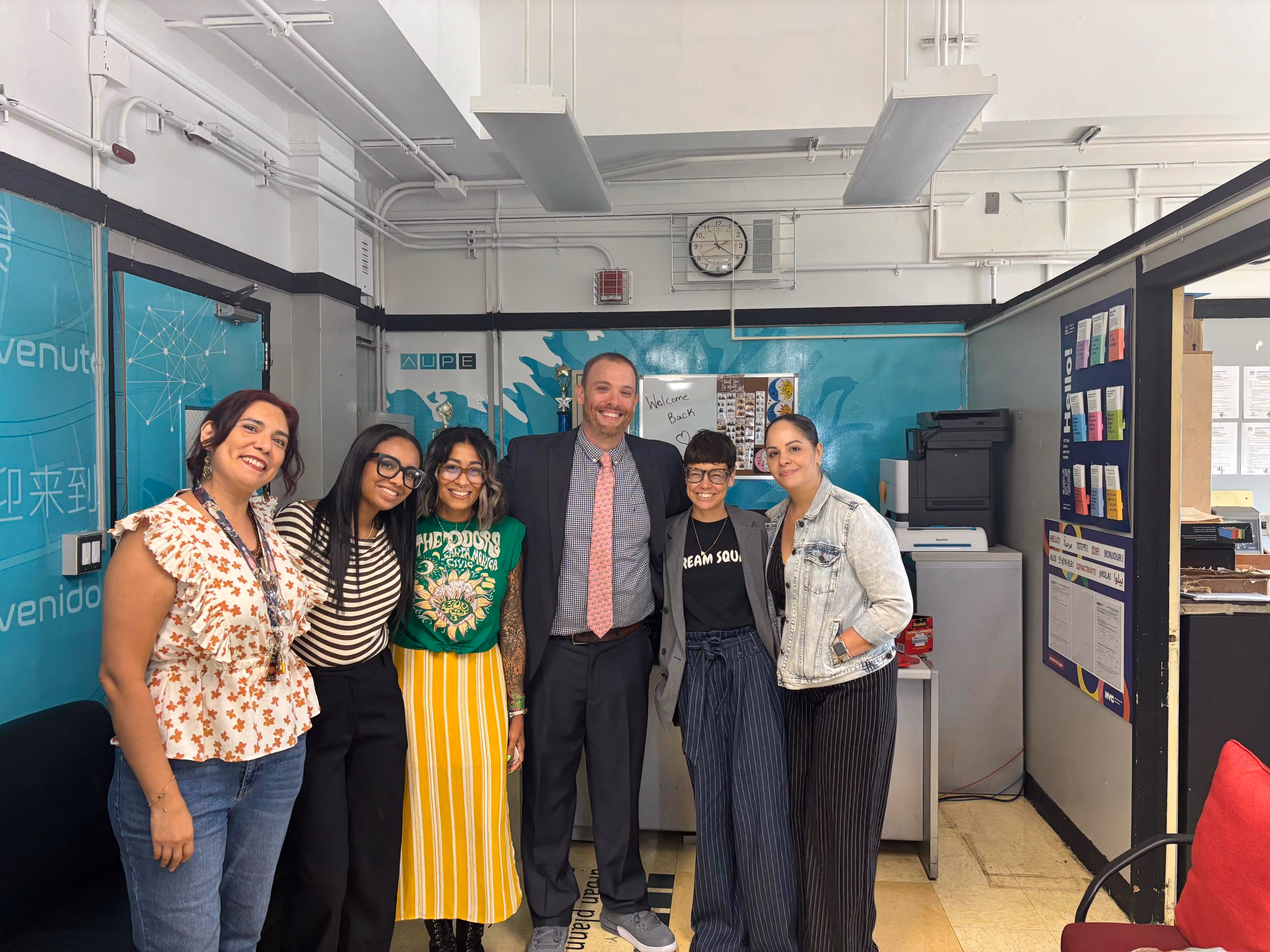 Group of six staff members posing together in school office