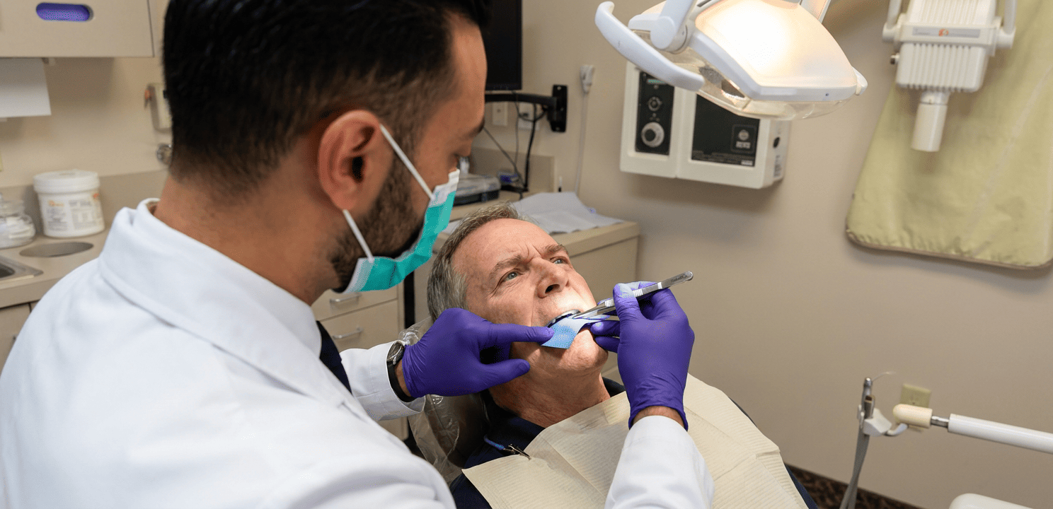 Dr. Khaddor positions articulating paper for patient's bite calibration for implant-supported bridges.