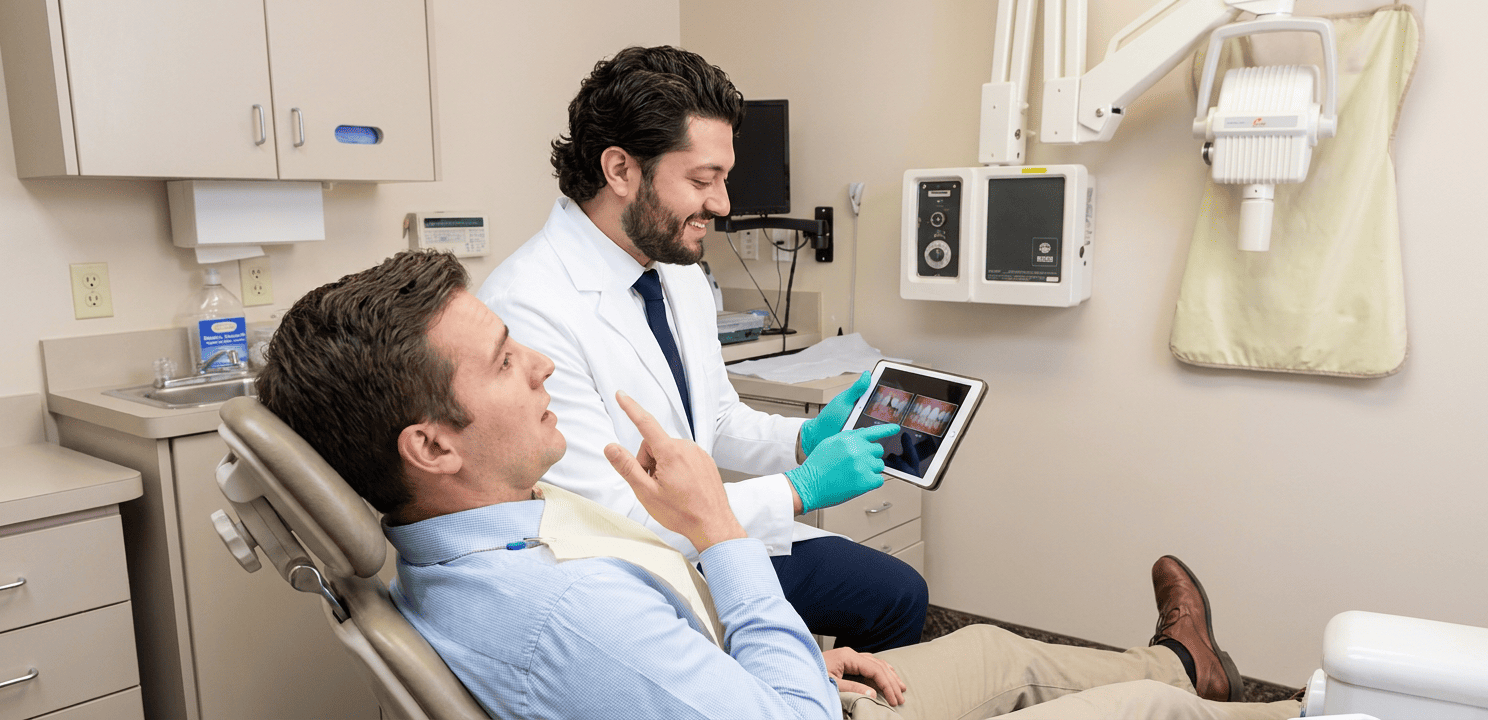 Dr. Kroni examines a chipped tooth and shows dental bonding options on a tablet during a consultation.