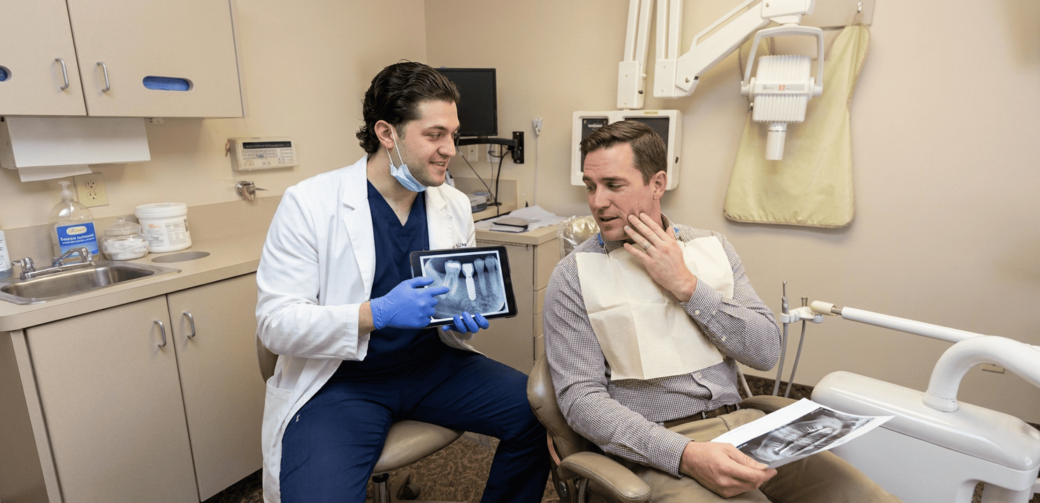 Dr. Kroni reviews a periapical x-ray with a patient, showing successful dental implant osseointegration.