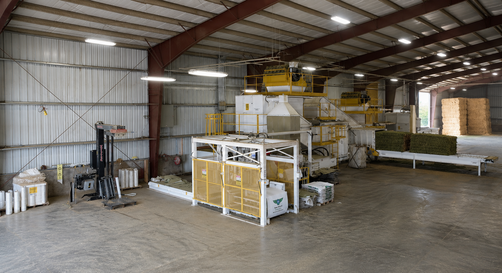 Interior of the Stone Wings II hay processing facility showing baling machinery, conveyors, and stacked hay bales