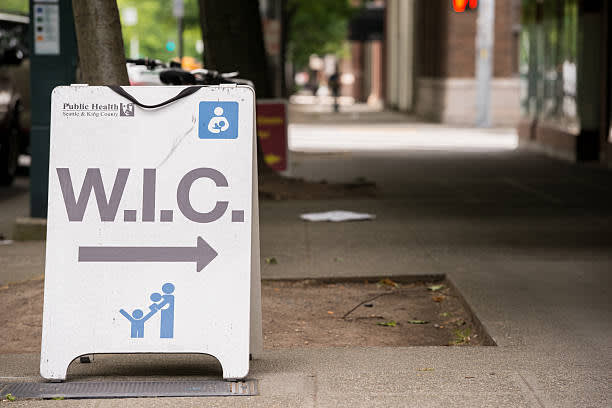 Sidewalk sign with the WIC logo and an arrow.