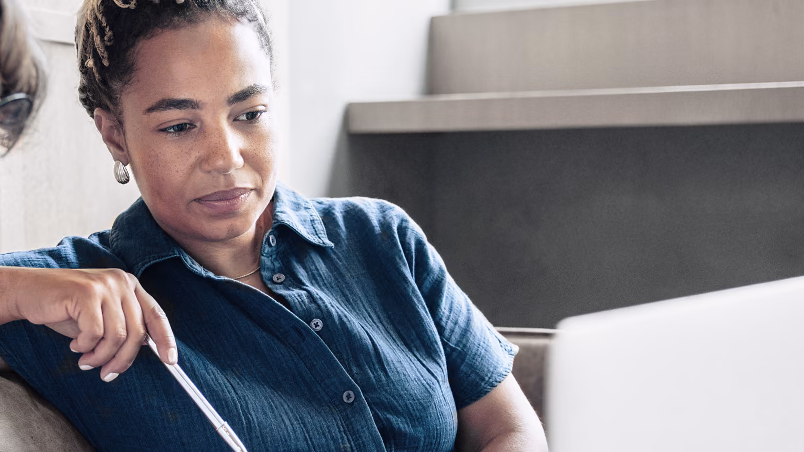 Two women sitting together looking at a laptop screen, one pointing at it with a pen, engaged in a discussion.