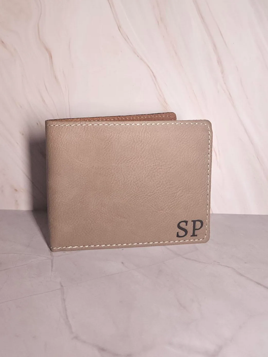 Tan leather bifold wallet engraved with the initials SP
