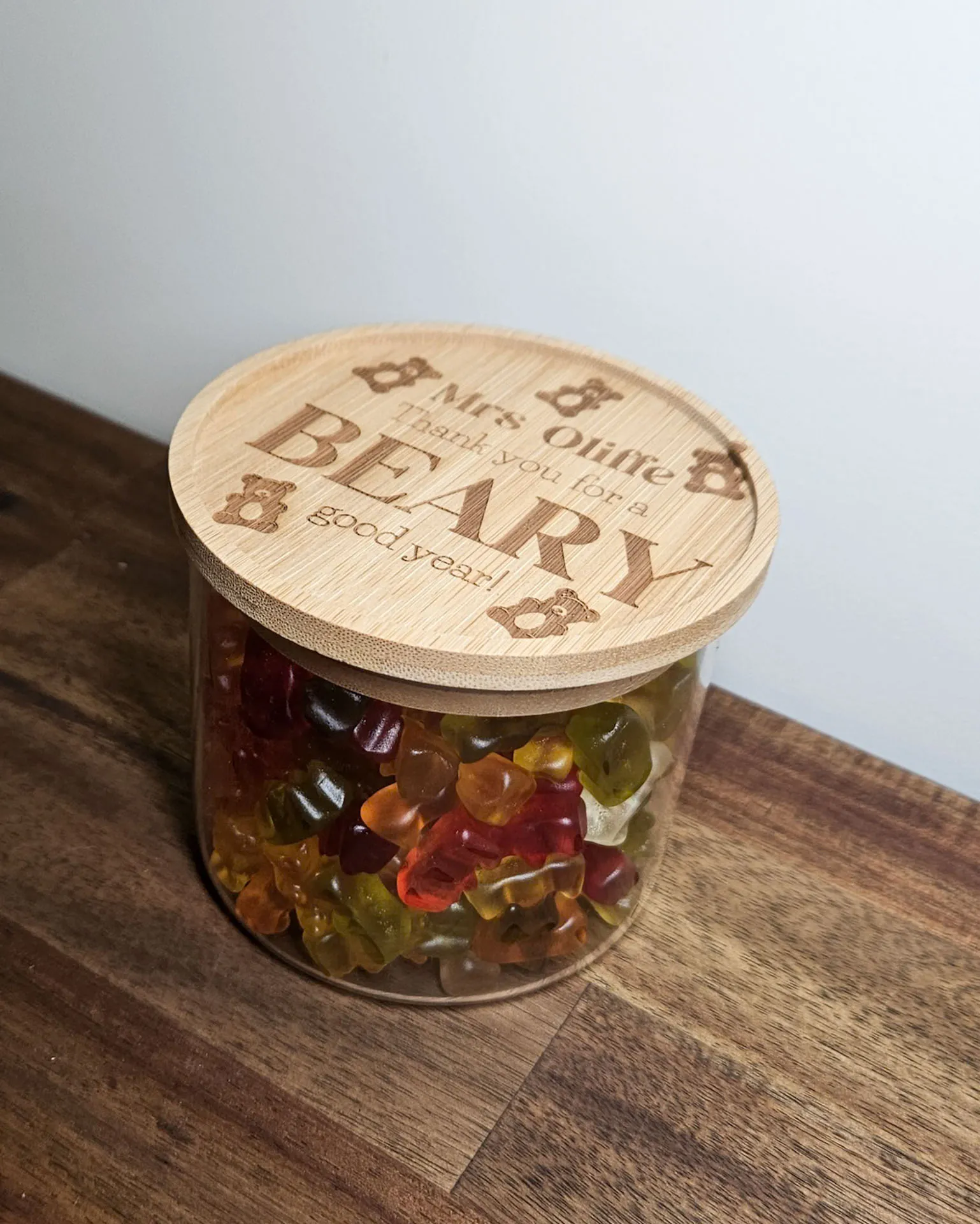Glass lolly jar filled with gummy bears, topped with an engraved timber lid reading Mrs Ohne, thank you for a beary good year