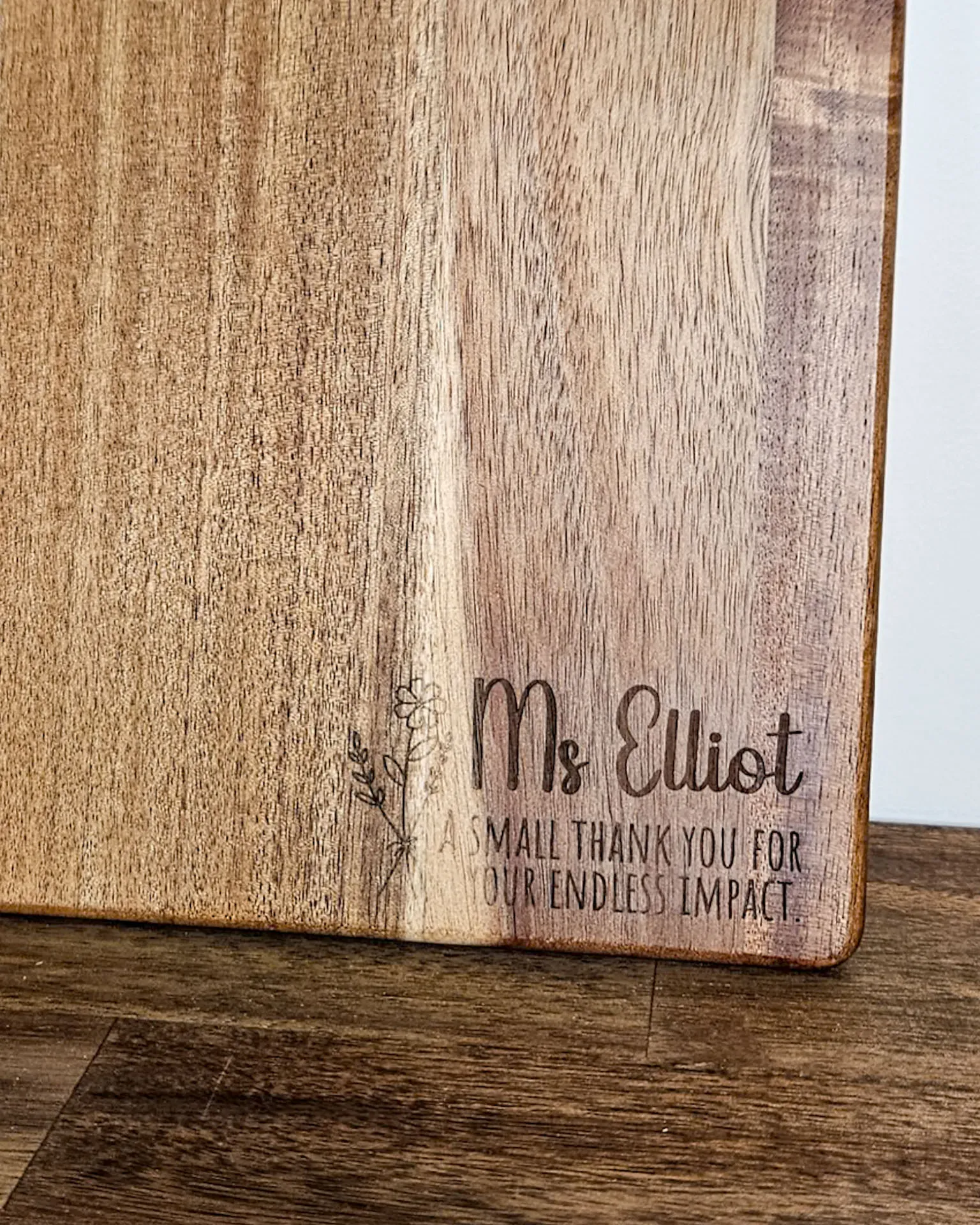Timber serving board engraved Ms Elliot, a small thank you for your endless impact, with a wildflower sprig