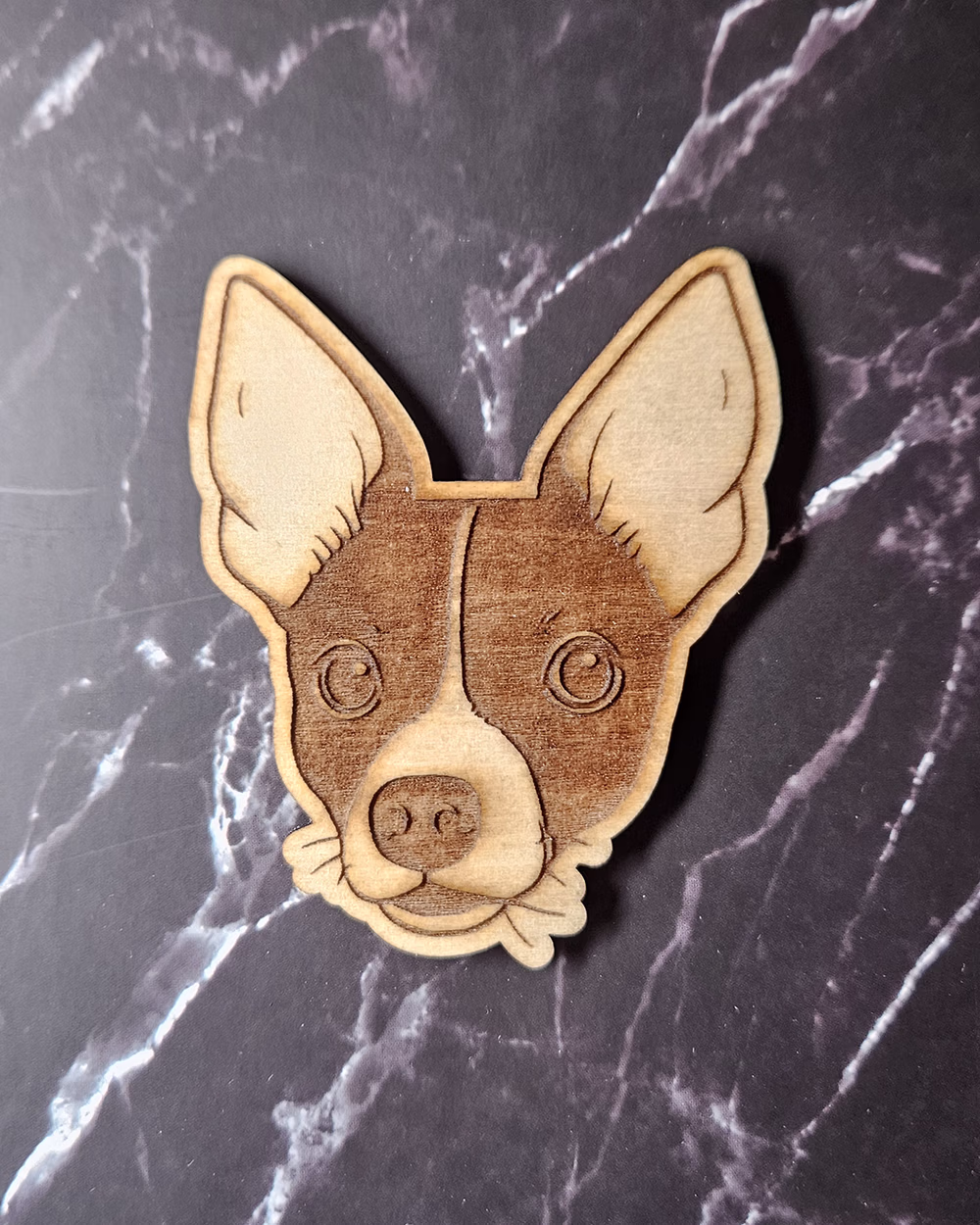 Laser-engraved timber pet portrait magnet of a black and white dog with tall pointed ears