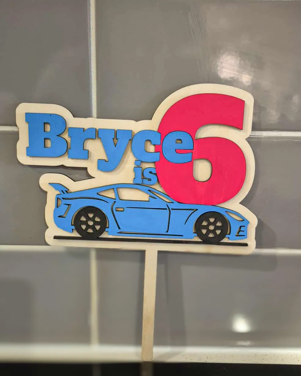 Timber cake topper reading Bryce is 6 with a layered blue race car