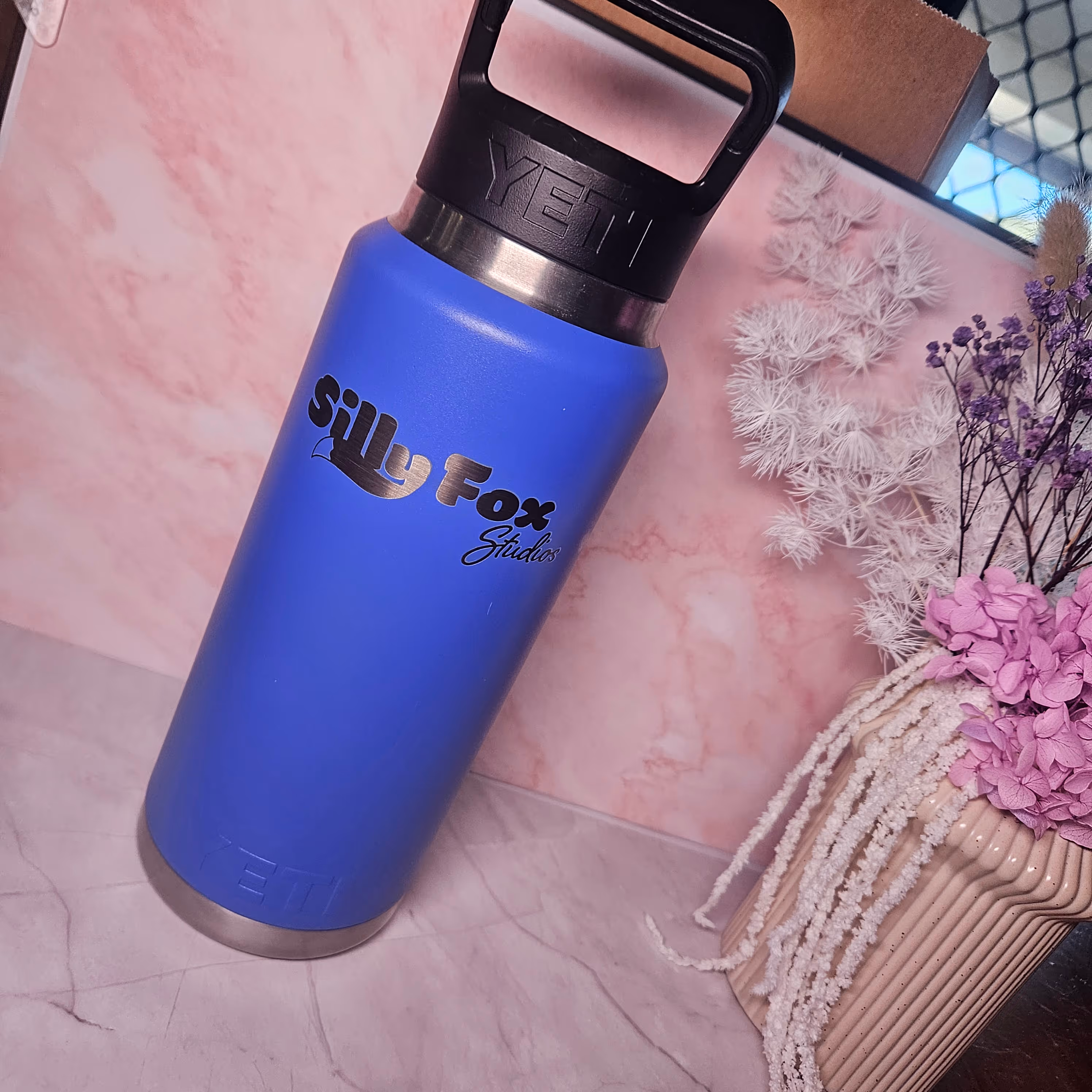 A blue insulated drink bottle engraved with the Silly Fox Studios logo