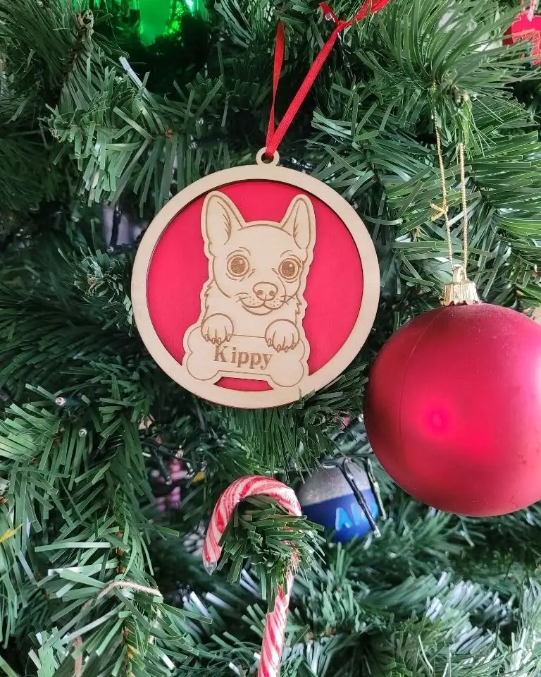A round timber Christmas ornament engraved with a dog portrait and the name Kippy