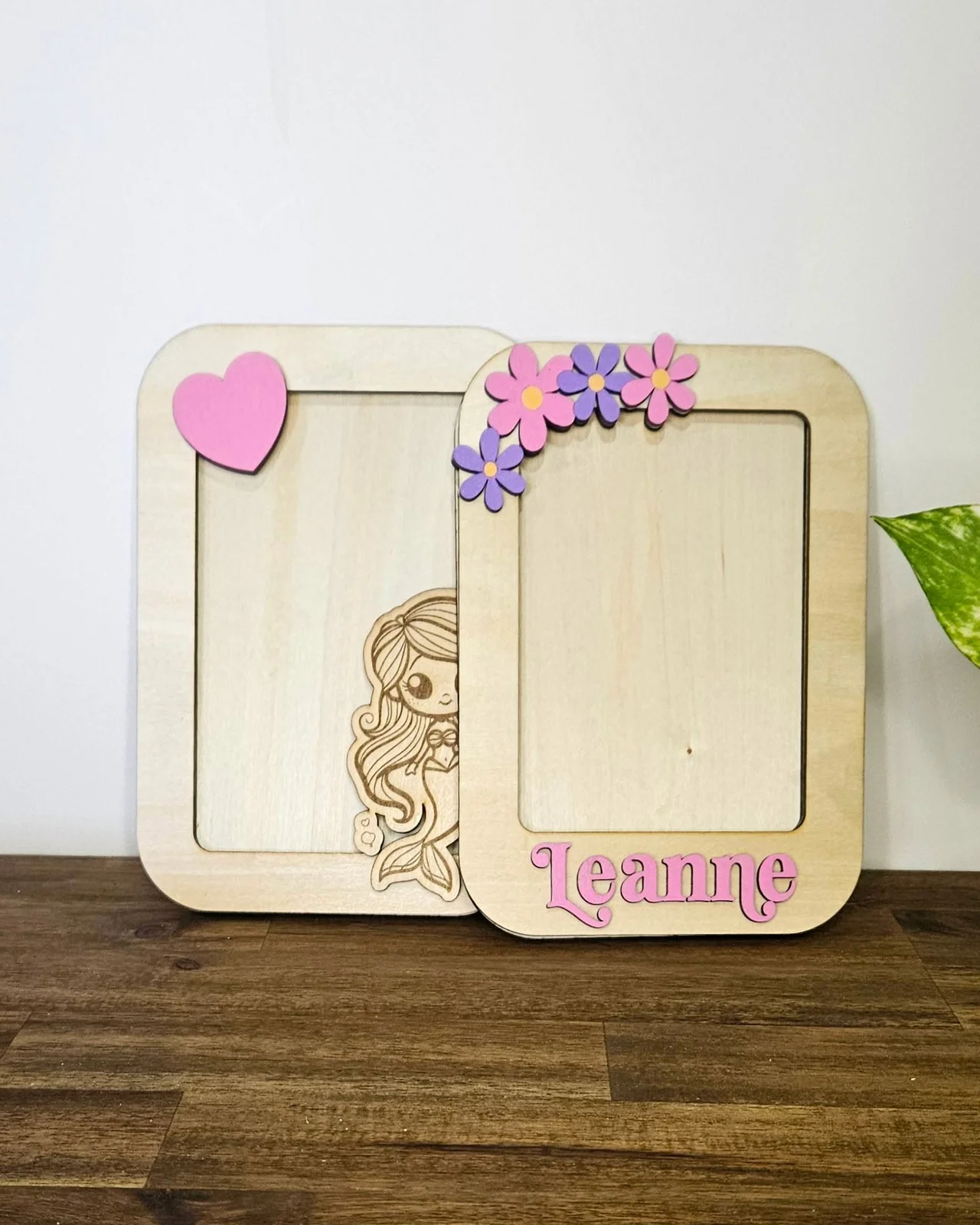 Two timber photo frames, one engraved with a girl illustration and the name Leanne