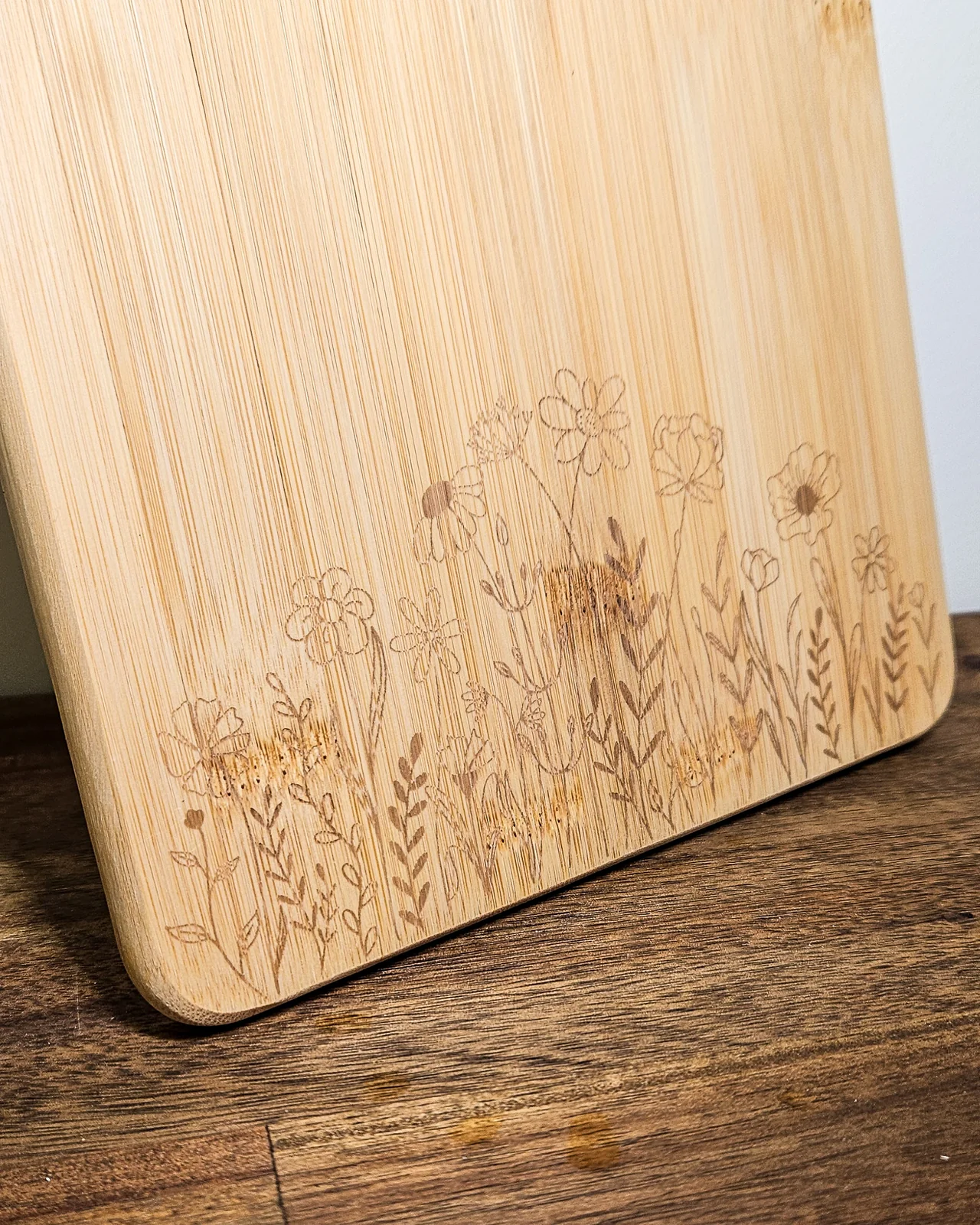 A bamboo cutting board engraved with a wildflower design