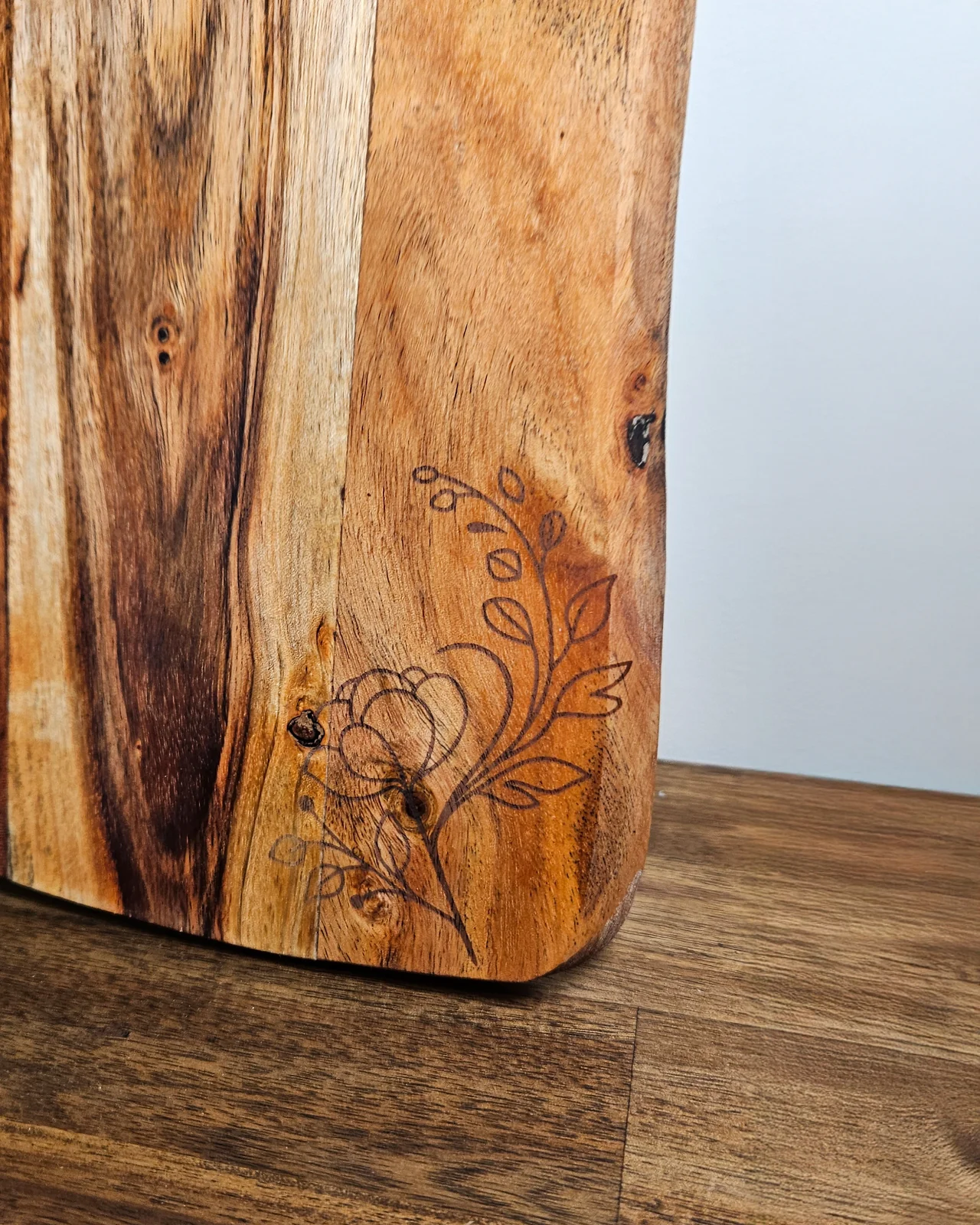 A dark timber serving board engraved with a delicate floral design