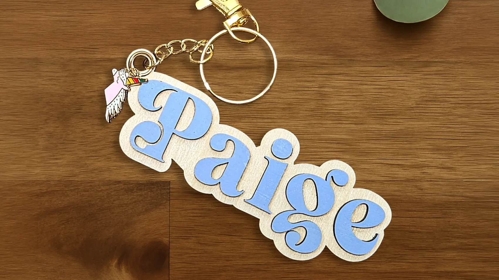 A wooden keyring with 3D letters spelling the name Paige in periwinkle.