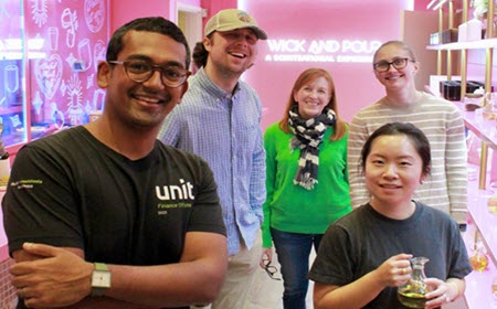Team smiling in front of the neon Wick and Pour sign after a candle making team building event
