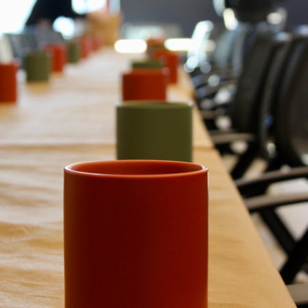 Row of colorful candle vessels lined up on a long table for a corporate candle making event