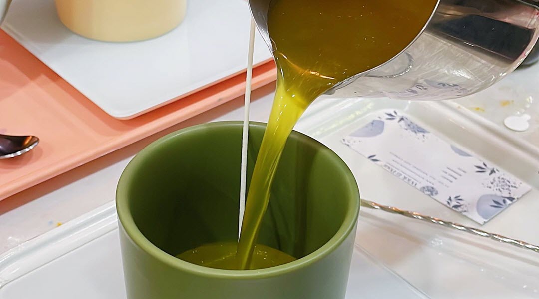 Melted wax being poured into a green candle vessel at Wick & Pour