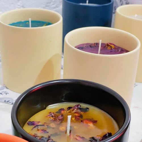 Three handmade candles decorated with dried flowers at Wick & Pour