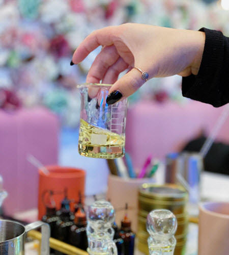Fragrance oil measured in a glass beaker above a candle making station at Wick & Pour
