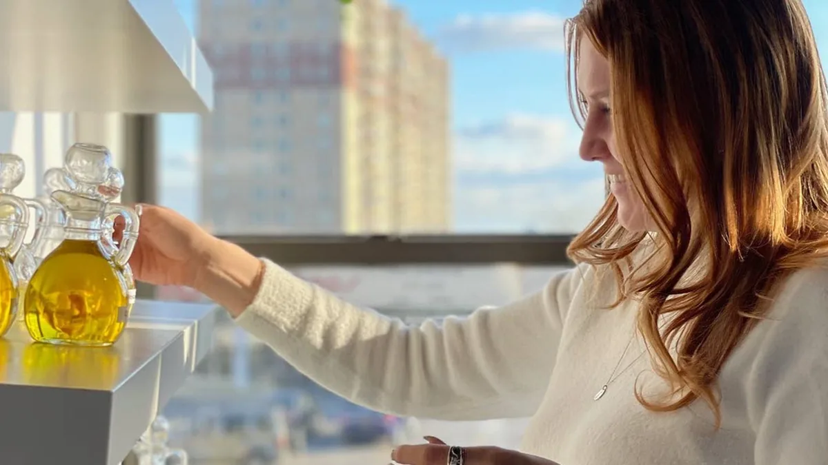 Woman reaching for a bottle of fragrance oil by a sunny window