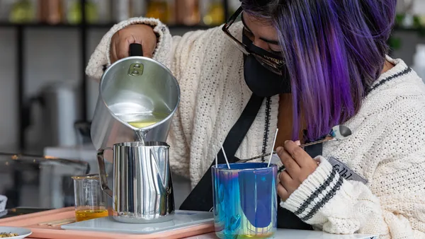 Guest carefully pouring wax into a candle vessel during a celebration at Wick & Pour