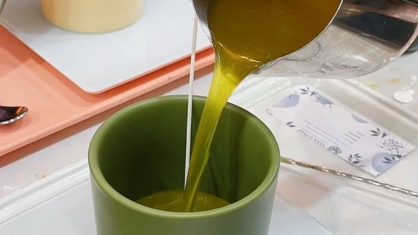 Melted wax poured into a green candle vessel at Wick & Pour