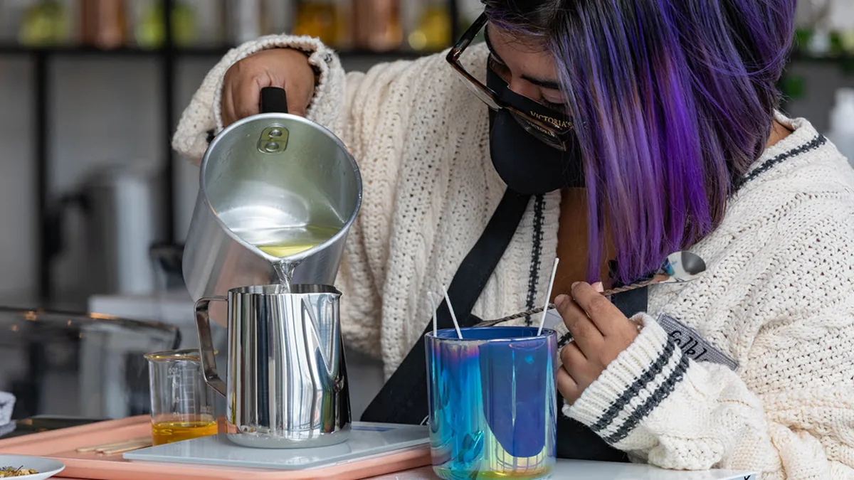 Guest carefully pouring wax into a candle vessel during a celebration at Wick & Pour