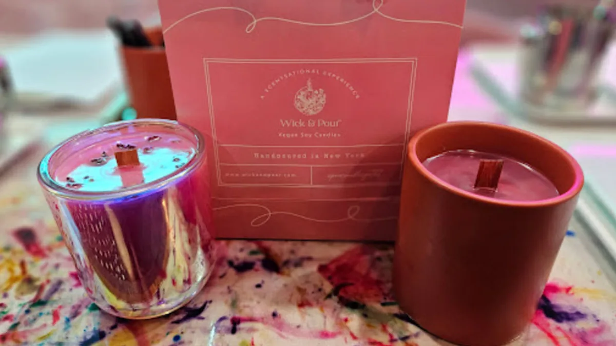 Two handmade candles with crackling wooden wicks beside a Wick & Pour gift bag