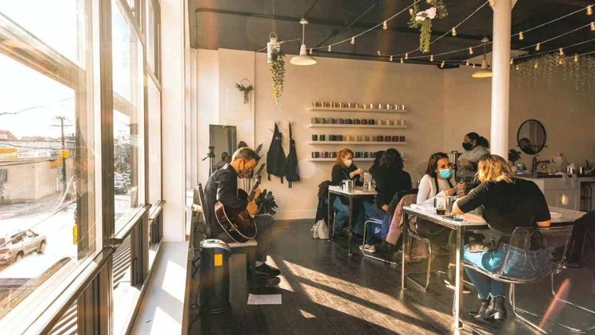 Guests making candles at tables in a sunlit space during a candle making class