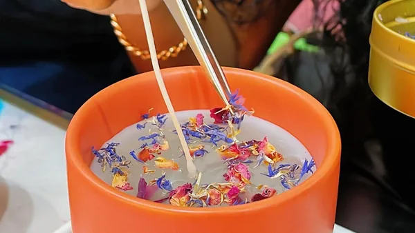 Decorating a candle with dried flowers and tweezers at a Wick & Pour candle making class