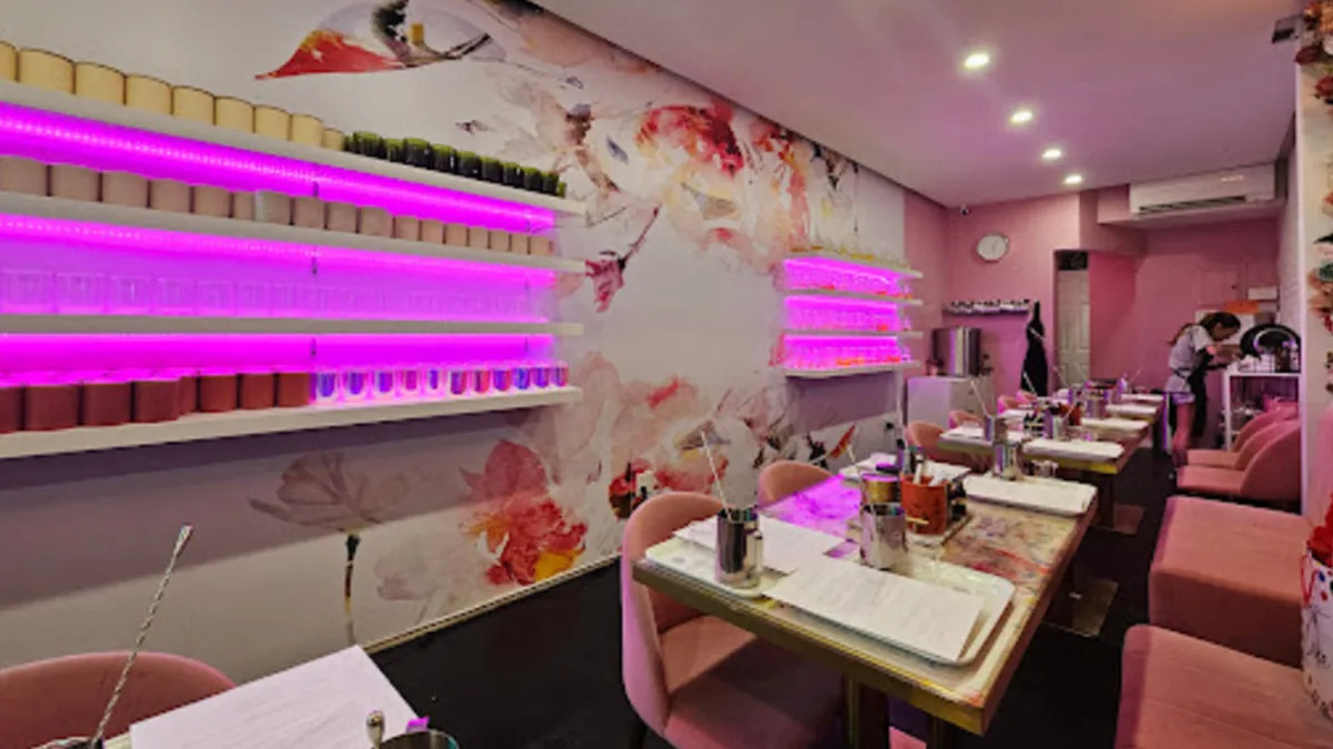 Wick & Pour candle making studio with glowing pink shelves, a floral mural and tables set for a private class