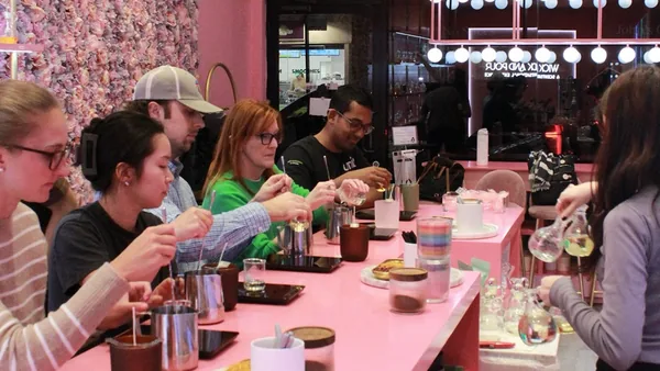 Friends measuring and pouring at the pink bar during a group candle making class at Wick & Pour