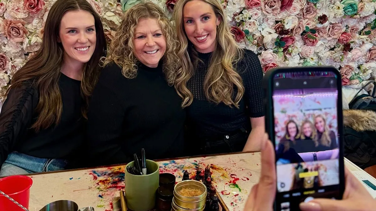Three friends taking a selfie at a candle making table during a bachelorette party at Wick & Pour