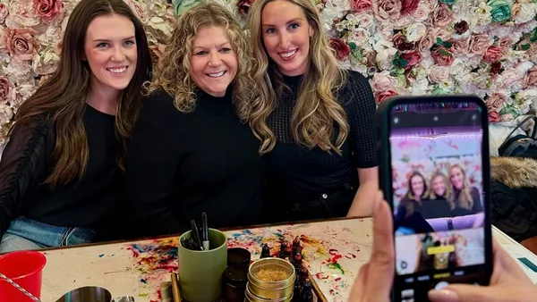 Three friends taking a selfie at a candle making table during a bachelorette party at Wick & Pour