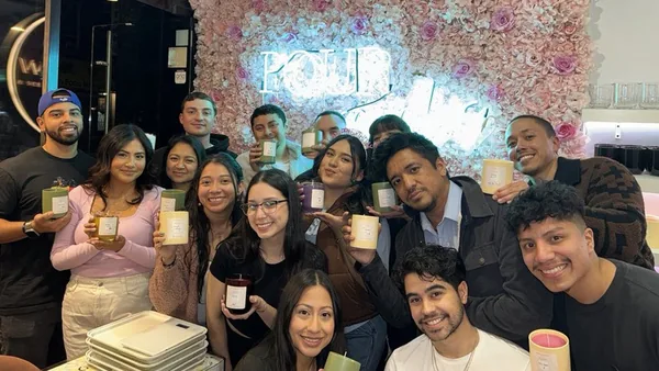 Team holding the candles they made together at a Wick & Pour team building event in NYC