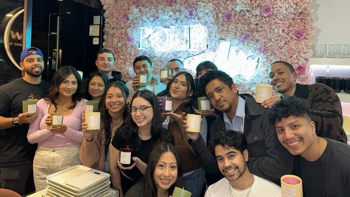 Team holding the candles they made together at a Wick & Pour team building event in NYC